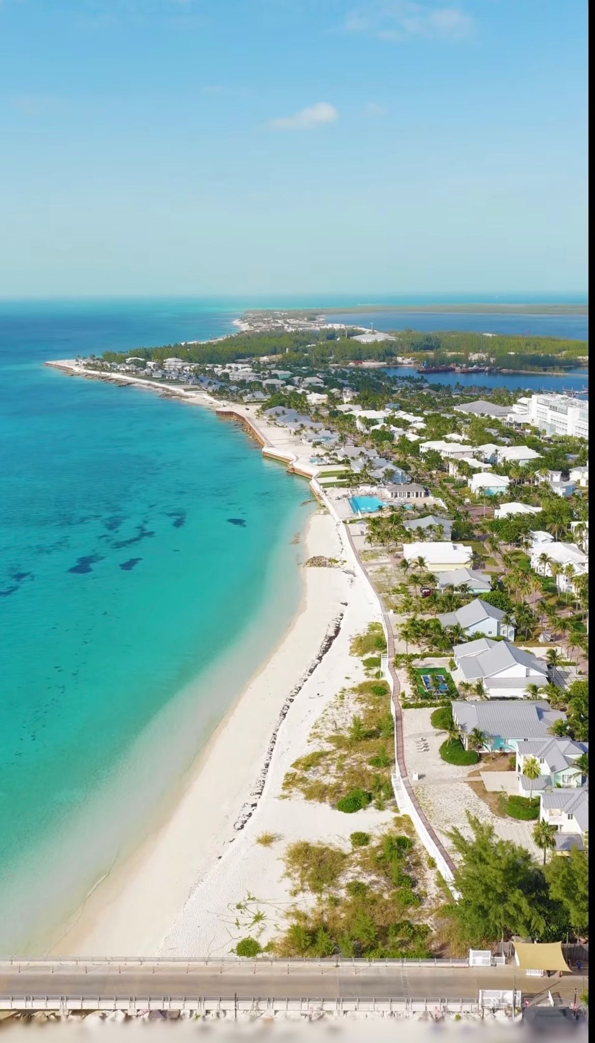 Aerial of a long white-sand beach and coastal homes