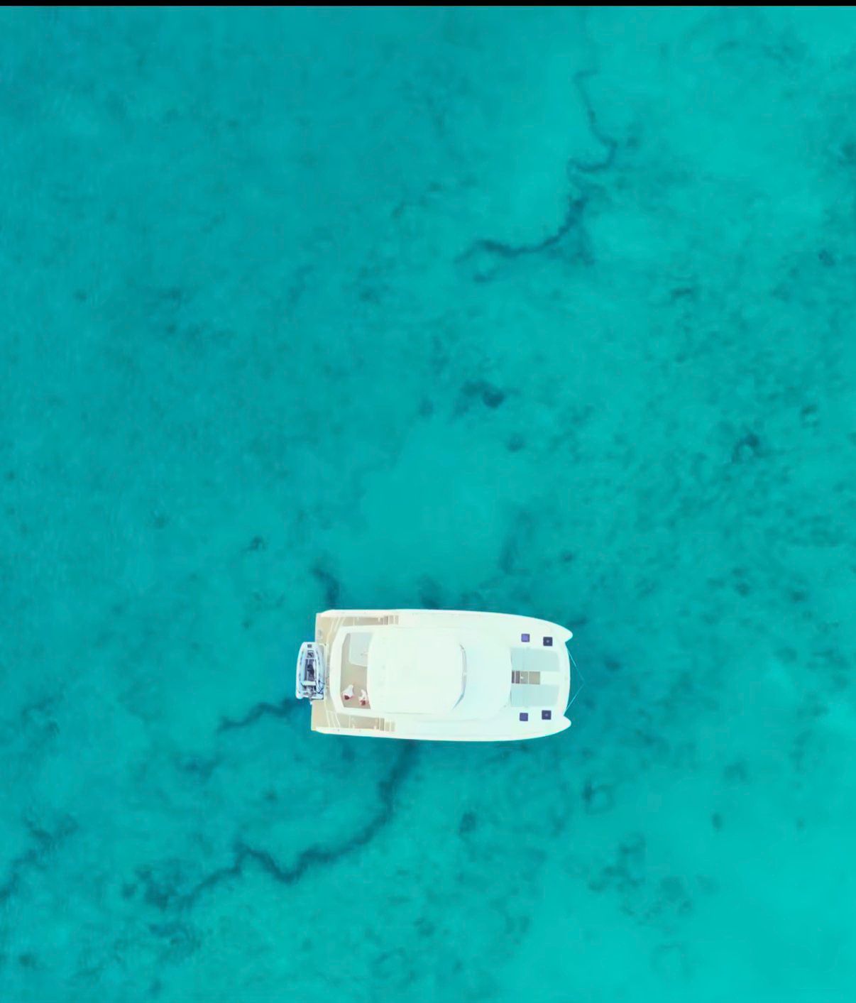 White catamaran from above in clear tropical water
